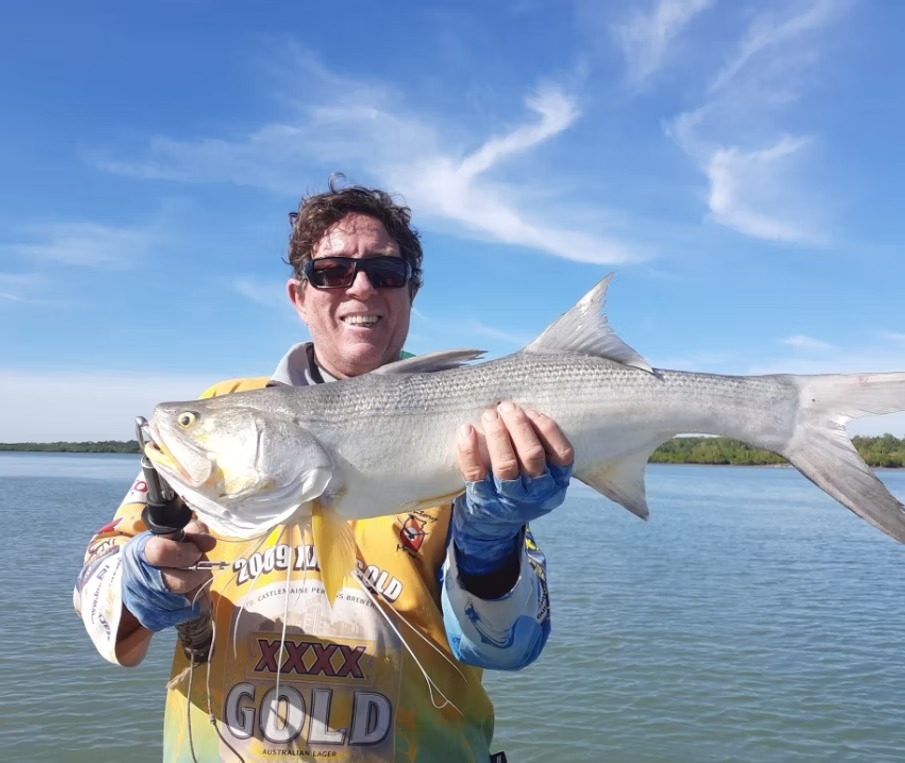 Angler on the flats holding a threadfin salmon taken on fly near Darwin
