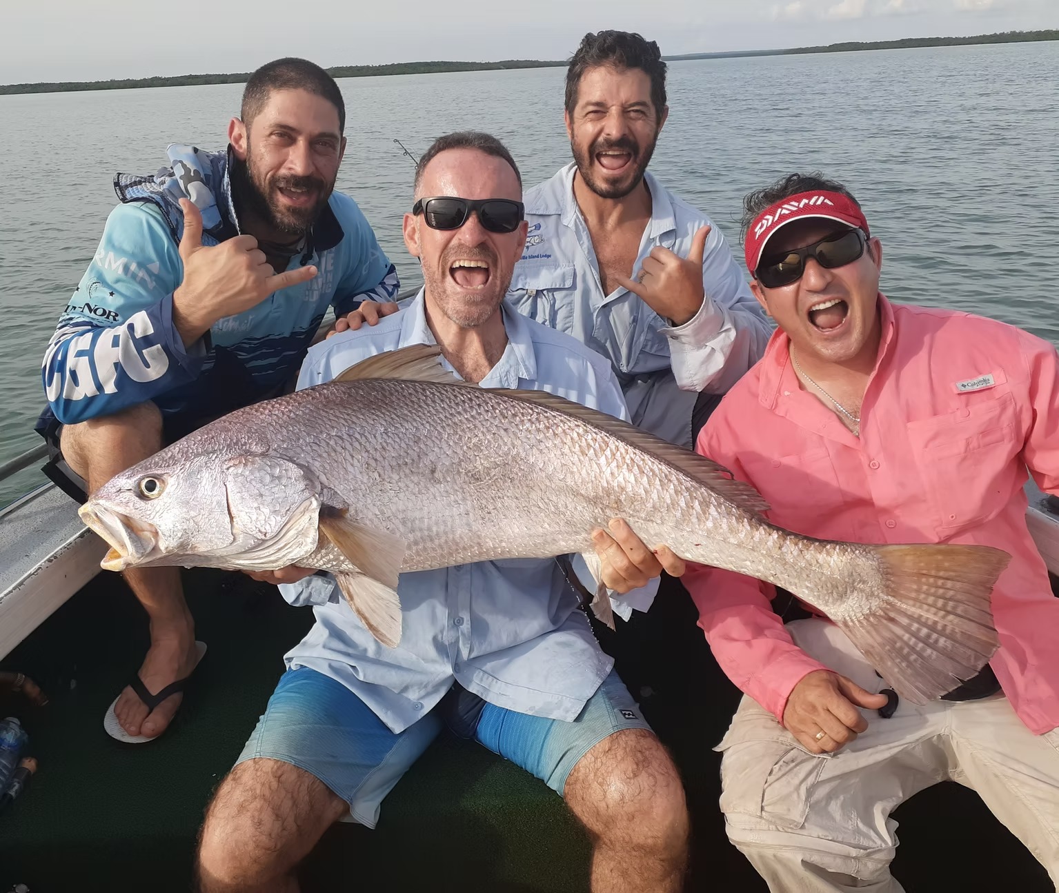 Four anglers on a boat celebrating with a huge black jewfish caught off Darwin