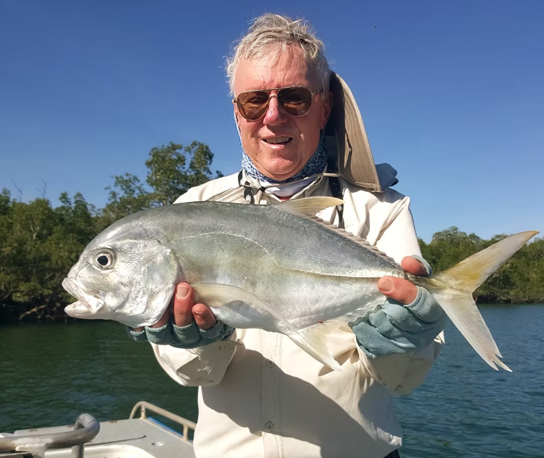 Angler holding a trevally with mangroves in the background at Bynoe Harbour